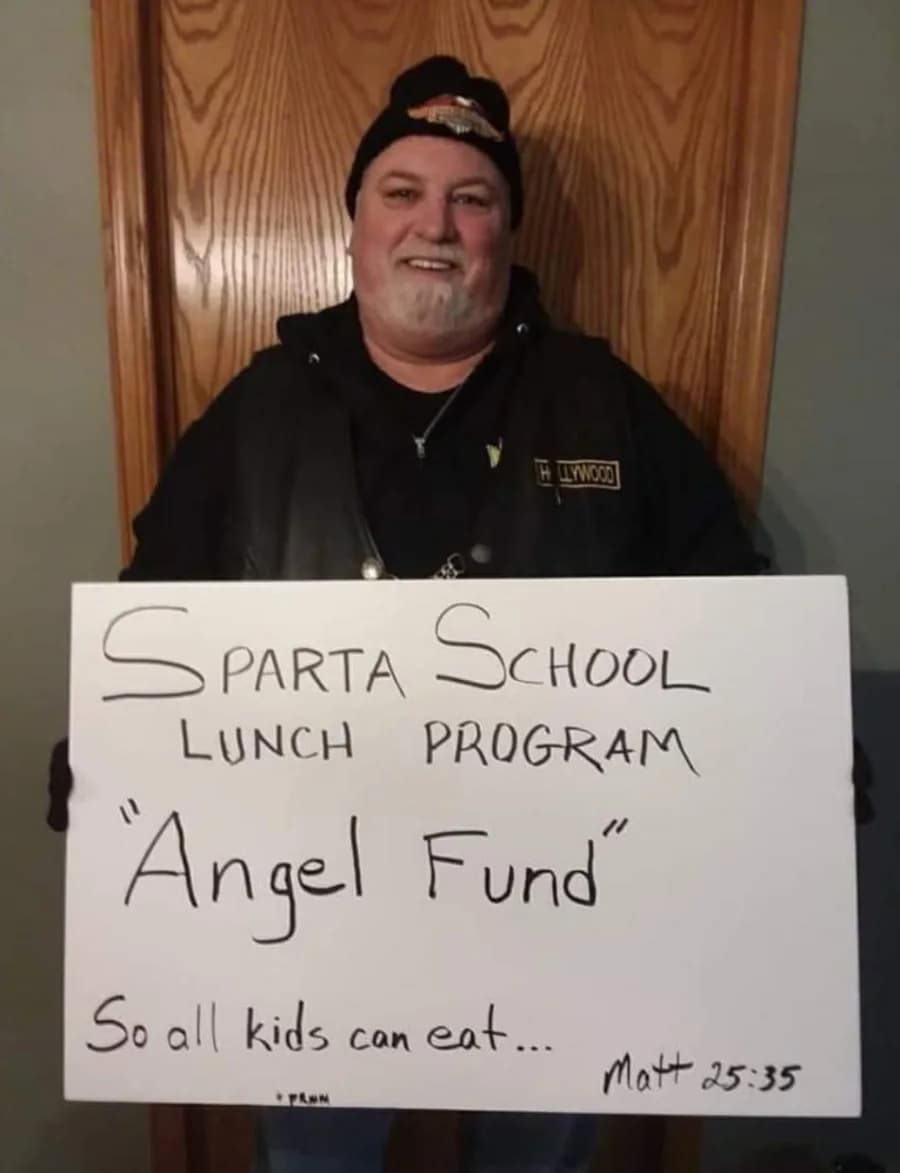 John Harrison holding his original handmade Sparta School Lunch Program Angel Fund sign